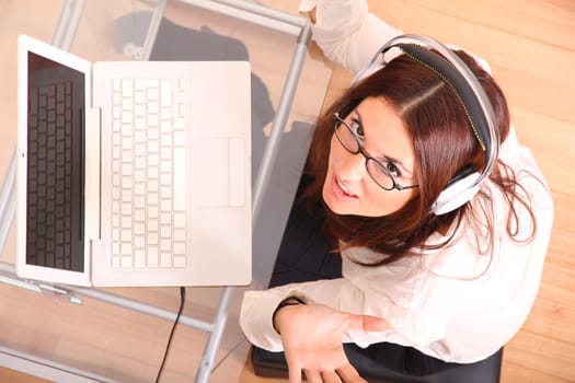 Business woman working on a Laptop while listening music with Headphones.