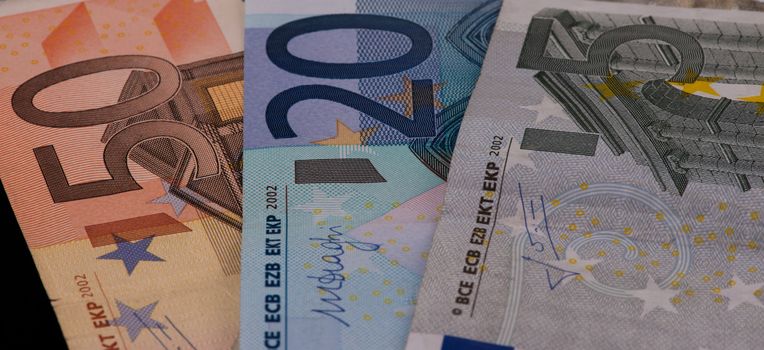 Five, Twenty and Fifty Euro bills on black background.