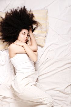 A young latin woman lying down in bed.