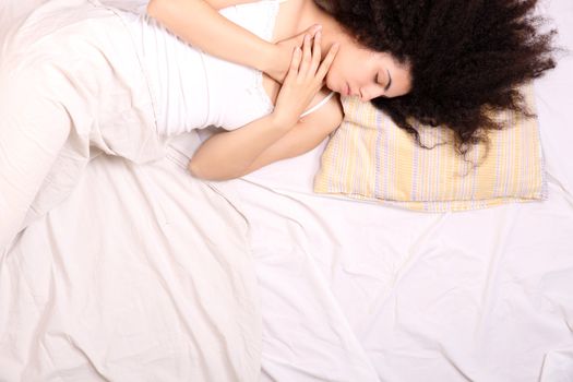 A young latin woman lying down in bed.