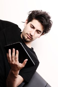 A young hispanic man sitting on the sofa holding a Tablet PC.