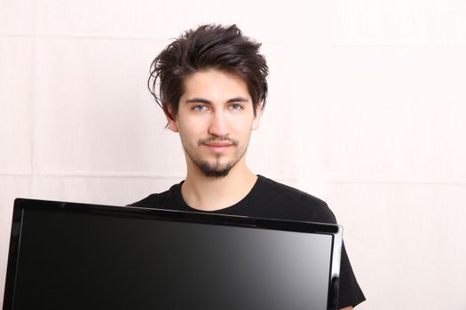 A young hispanic man holding a flatscreen TV.