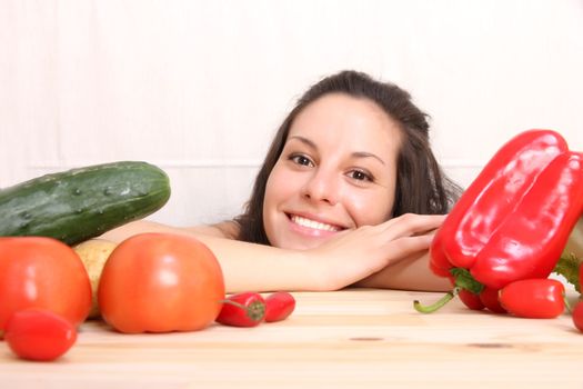 A young hispanic girl in the kitchen between vegetables.