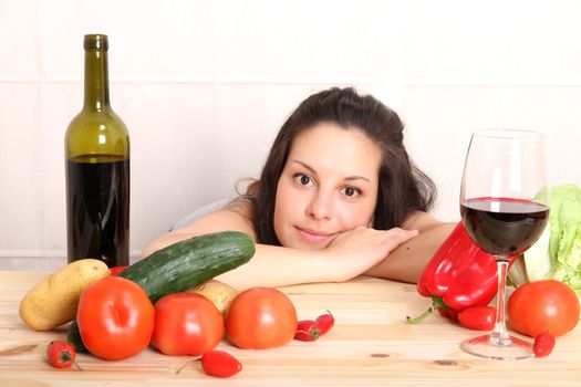 A young hispanic girl in the kitchen between vegetables.