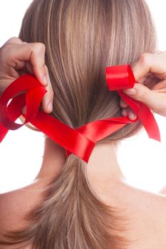 Young woman braids her hair with red ribbon