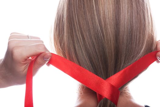 Young woman braids her hair with red ribbon