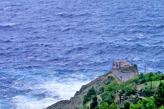 Chapel on rocky coast seen from above. Stormy weather.