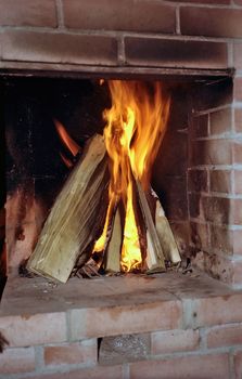 Burning wood in fireplace from red brick