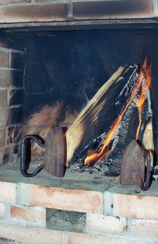 Two old irons in fireplace near burning wood