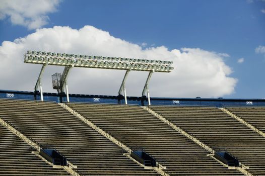 Stadium lights above empty seats with a cloud in the background.