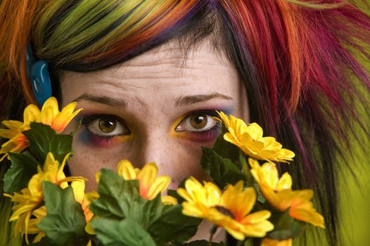 Pretty young woman peeks out from behind plastic flowers.