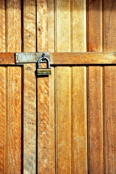 wooden door locked with a golden padlock