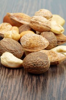 Heap of Mixed Nuts with Cashew, Macadamia, Peanut, Almond closeup on Dark Wood background