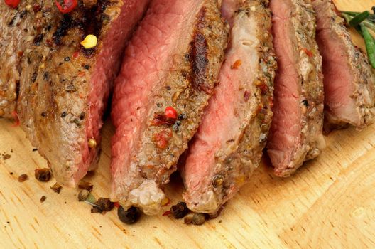 Arrangement of Sliced Ripe Roast Beef with Spices closeup n Wood Cutting Board