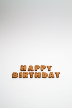 the words Happy Birthday made by brown biscuits on white surface in portrait orientation