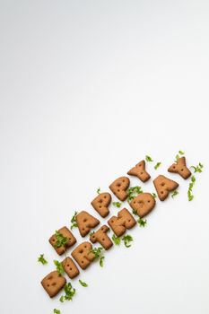 the words Happy Birthday made by brown biscuits and green leaves slanting on lower side of white surface in portrait orientation