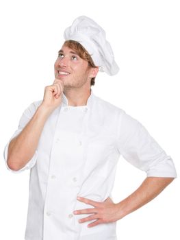 Thinking chef, baker or male cook. Young man in chefs whites uniform smiling happy looking up. Portrait of young chef in his twenties.