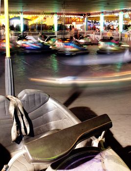 A Vehicle Stands Unused in a motion blurred photo of Bumper Cars at the Fair