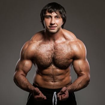 Happy muscular guy posing on a grey background