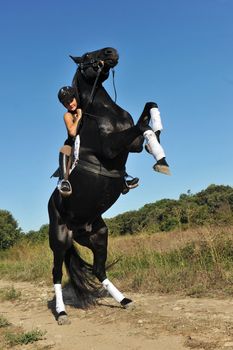 young woman and her beautiful black stallion rearing up