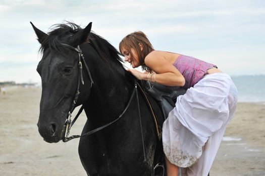 beautiful black  horse on the beach and beautiful woman mount it
