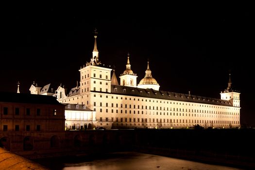 San Lorenzo de El Escorial Monastery  at night beautifully illuminated. Four towers are set off by black background.