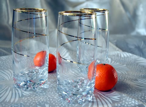 Three glasses, decorated with gold spiral pattern, and two tangerines