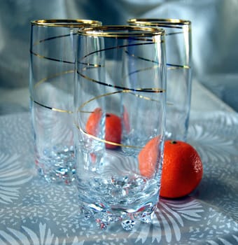 Three glasses, decorated with gold spiral pattern, and two tangerines