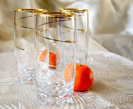 Three glasses, decorated with gold spiral pattern, and two tangerines