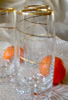 Three glasses, decorated with gold spiral pattern, and two tangerines