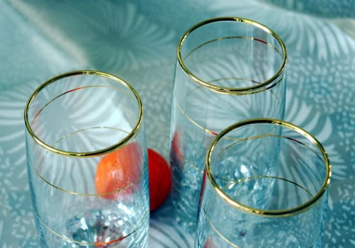 Three glasses, decorated with gold spiral pattern, and two tangerines