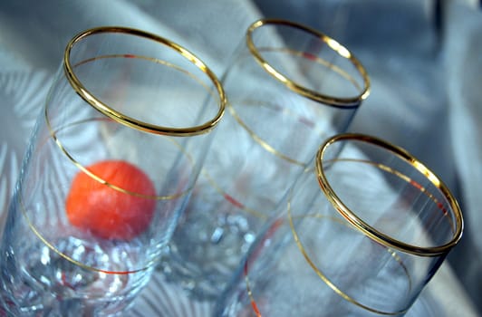Three glasses, decorated with gold spiral pattern, and two tangerines