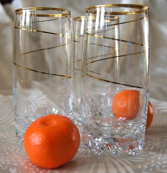 Three glasses, decorated with gold spiral pattern, and two tangerines