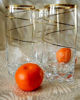 Three glasses, decorated with gold spiral pattern, and two tangerines