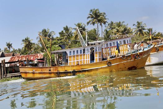 25 Spetember 2011 Landscape of Kerala Backwaters with yellow fishing boat trawling for a catch, coconut palm shoreline and relatively clear blue sky. Editorial, crop margins and negative space