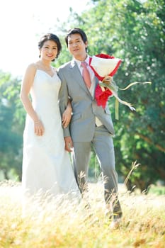 couples of bride and groom standing over meadows field