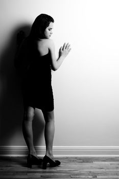 black and white portait or a woman leaning on wall