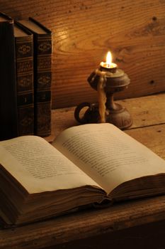 old book on a wooden table by candlelight