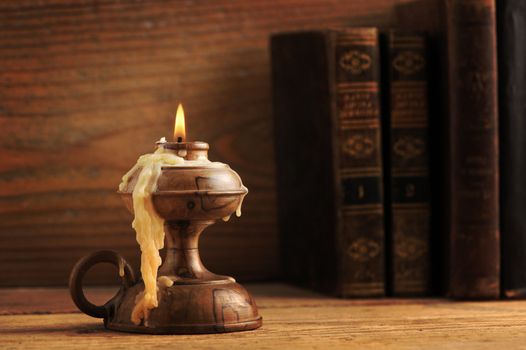 old candle on a wooden table, old books in the background