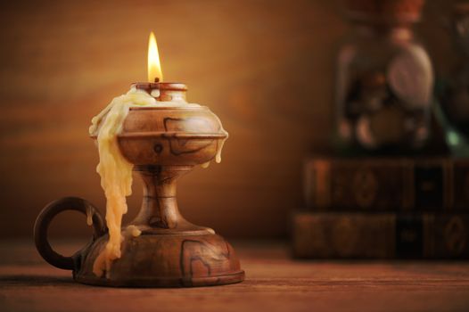 old candle on a wooden table, old books in the background