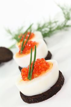 Canapes with boiled egg, chives and caviar