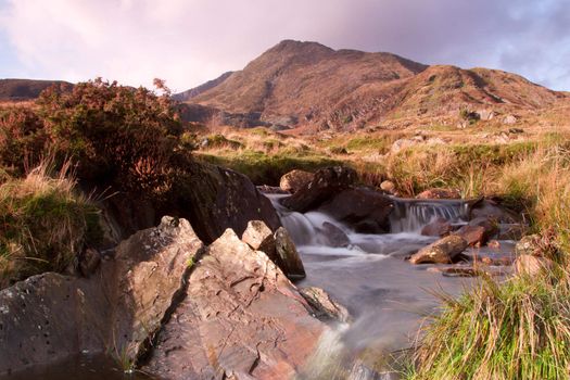 A stream in the foreground leads to the Welsh mountain peak Moel Siabod situated in the Snowdonia National park.