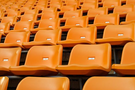 Orange Empty plastic seats at stadium open door sports arena