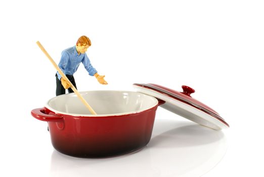 plastic puppet man stirring in red empty saucepan