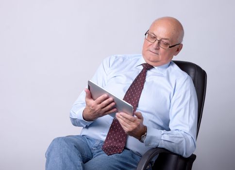 portrait of a successful senior man with tablet on gray background