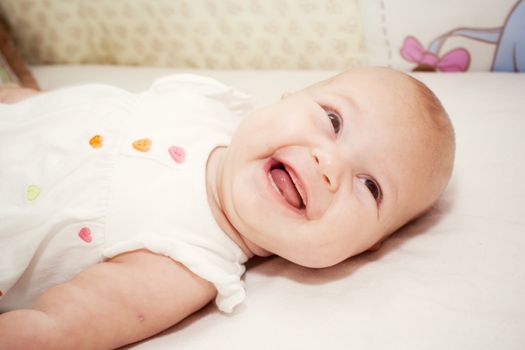 the portrait of little girl in her bed smiling and showing her hand