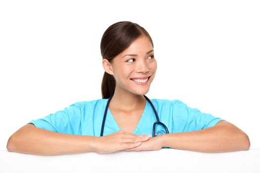 Medical sign or banner for edge. Woman nurse or young doctor in scrubs looking to the side showing empty blank paper sign isolated on white background. Young multiracial medical professional.