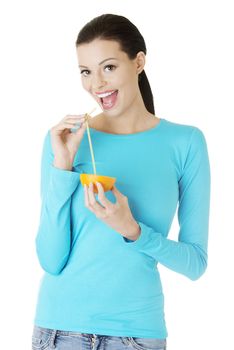 Attractive smiling young woman drinking orange juice straight from fruit