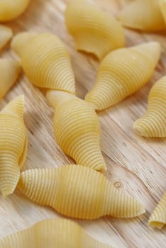 Big pasta shells or conchiglioni on the wooden table