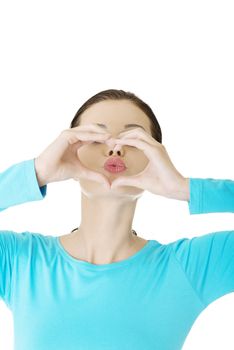 Attractive young woman showing heart gesture with hands and sending kiss